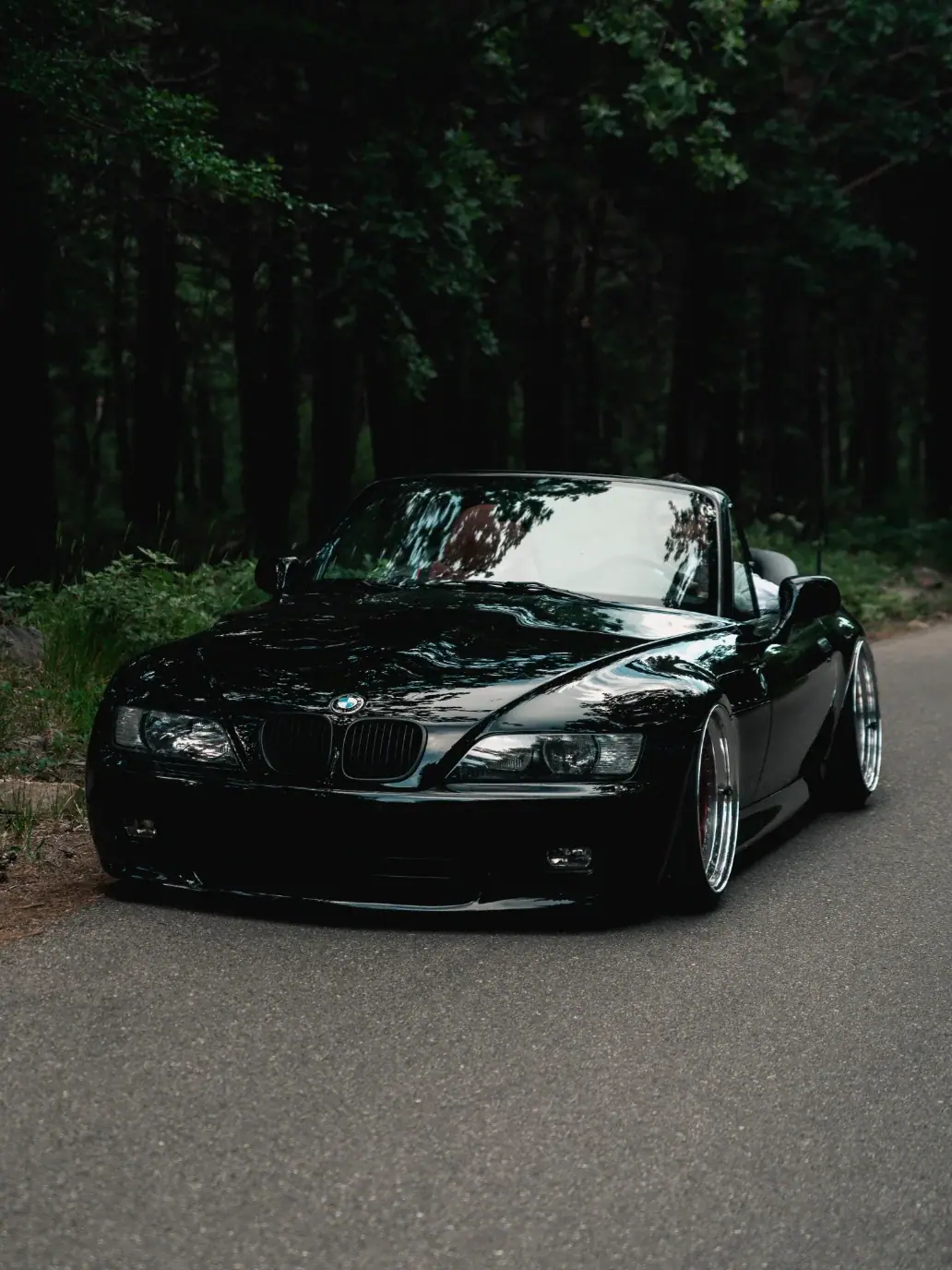 BMW Z3 negro en una carretera entre árboles