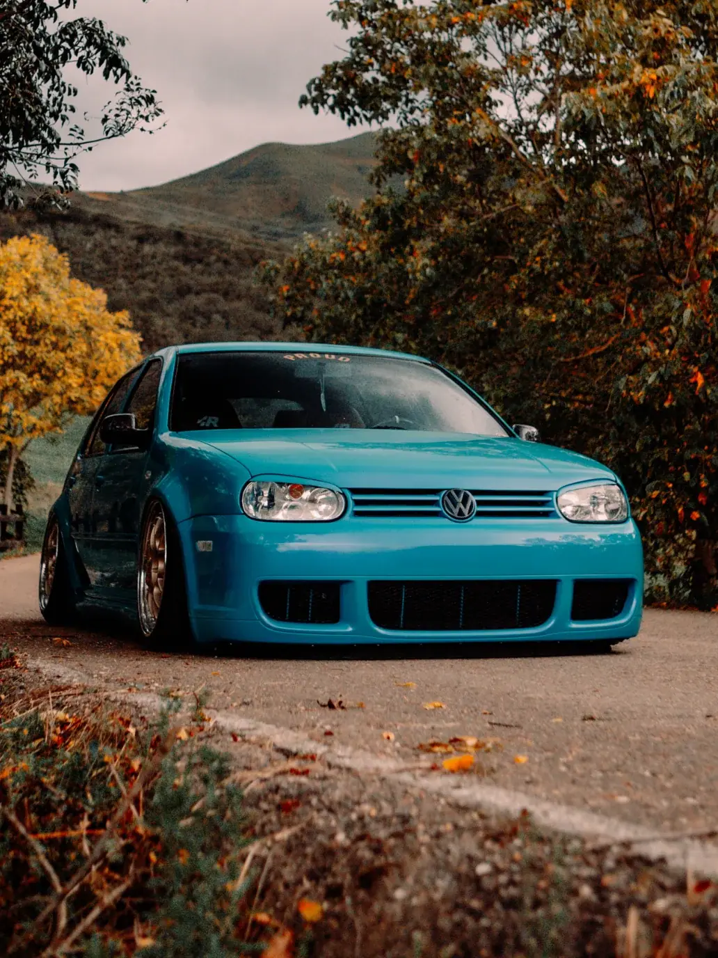 Volkswagen Golf IV azul en un camino de otoño